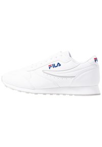 Vita sportskor i syntetiskt material med en strömlinjeformad design, snörning och Fila-logotyp i blått och rött på sidan.