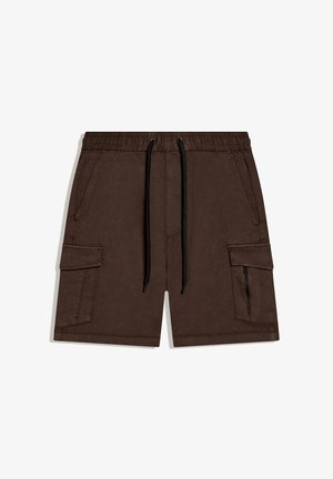 Brune cargoshorts med elastisk talje, sorte snore, sidelommer med klap og en lomme med lynlås på højre ben.