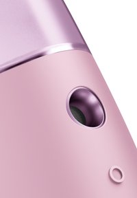 Appareil électronique rose avec une finition lisse et mate, un accent brillant en haut et un bouton circulaire. Présente une ouverture ronde.