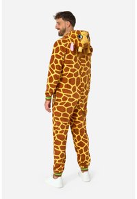 Tutina in pile marrone e giallo con motivo giraffe, dotata di cappuccio con orecchie, coda e polsini a coste verdi ai polsi e alle caviglie.