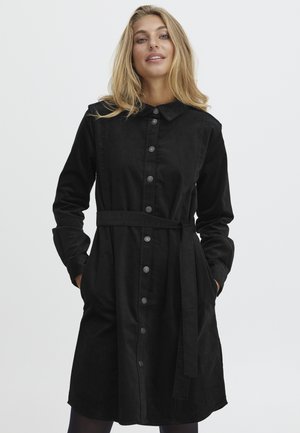 Robe noire à boutons, fabriquée en tissu doux, dotée d'un col, de manches longues, d'une taille ceinturée et de poches. Texture lisse sans motifs visibles.