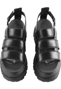 Black closed-toe sandals feature three horizontal straps, adjustable heel buckle, textured sole, and smooth synthetic upper material.
