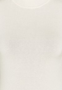 Pull en maille blanche à col roulé, fabriqué en tissu doux et extensible. Il présente un col haut et une silhouette ajustée avec une texture lisse.