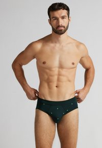 Zelené bavlněné trenýrky s tečkovaným vzorem, elastickým pasem a klasickým střihem. Hladký povrch a přiléhavý design.