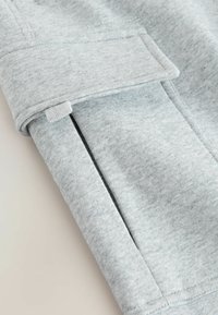Grauer Pullover aus einem glatten Material, mit umgeschlagenem Bündchen und seitlichen Schlitzen, aus dehnbarem Stoff für Komfort und Bewegungsfreiheit.