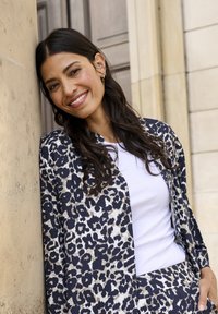 Leopardmuster-Jacke mit weißem strukturiertem Oberteil, mit langen Ärmeln und lässigem Schnitt, kombiniert mit einer passenden Hose.