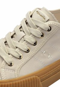 Leinenschuh in hellbeige mit geflochtenen Schnürsenkeln, goldfarbenen Ösen und einer geriffelten Gummisohle. Verfügt über dezente Steppnähte an der Seite.