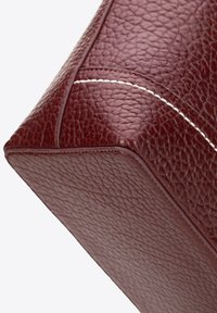 Sac à main en cuir bordeaux avec une surface texturée, des coins nets, des coutures blanches contrastantes et des accents lisses.