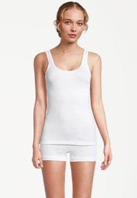 Canotta bianca in cotone con spalline larghe e scollo rotondo, abbinata a slip bianchi coordinati, caratterizzati da una texture liscia e un design aderente.