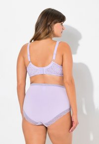 Conjunto de lencería lila que incluye un sujetador de encaje con tirantes ajustables y unas braguitas de talle alto a juego con un ribete de encaje. Textura suave y lisa.