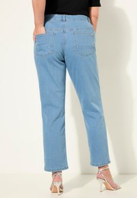 Ljusblå denimjeans med rak passform, två bakfickor och medelhög midja, i kombination med silvriga högklackade sandaler.