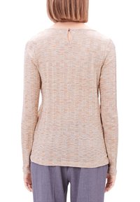 Långärmad topp i ljusbeige med en strukturerad zigzagmönster. Nyckelhålsdetalj vid halsringningen. Mjuk tyg och normal passform.