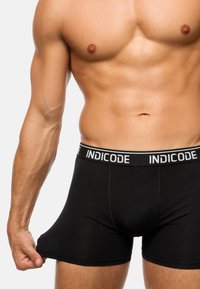 Schwarze Baumwollboxershorts mit einem elastischen Bund mit Markenlogo. Der Stoff ist glatt mit einer figurbetonten Passform und zeigt Nähte an den Seiten.