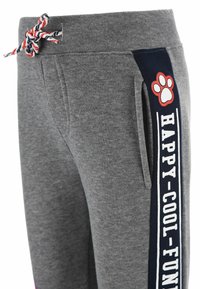 Grijze sweatpants met een marineblauwe zijpaneel waarop in witte tekst "HAPPY-COOL-FUN" staat, vergezeld van een rode pootafdruk accent. Inclusief een verstelbare taille met trekkoord.