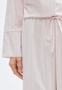 Ensemble de vêtements d'intérieur à rayures roses en tissu doux, avec manches longues, taille élastique et un cordon noué à la taille.