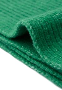 Tissu tricoté vert avec un motif texturé et côtelé. Le matériau semble doux et duveteux, affichant une couleur riche et uniforme sur toute sa surface.