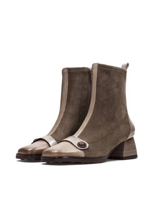 Stivali ankle in suede marrone con punta in pelle beige, zip laterale, cinturino decorativo, dettaglio a bottone rotondo e tacco a blocco.