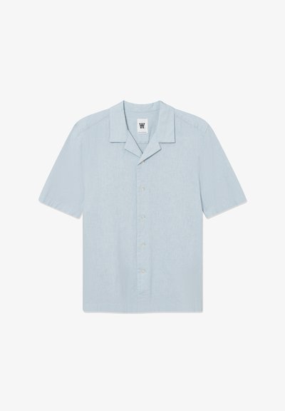 Chemise à manches courtes bleu clair en tissu texturé. Présente un col à entaille, une fermeture par bouton, et un petit logo brodé sur la poitrine.