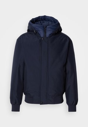 Giacca con cappuccio blu navy, chiusura con zip e bottone a pressione, polsini elastici e un'esterno testurizzato. Interno foderato in tessuto blu a contrasto.