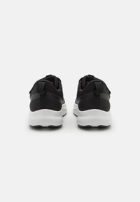 Baskets de sport noires avec une tige en mesh texturé, semelles blanches et languettes au talon pour un enfilage facile.