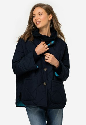 Giacca trapuntata blu navy con colletto alto, caratterizzata da accenti turchesi e due tasche anteriori. Chiusura con bottoni e dettagli di cucitura in evidenza.
