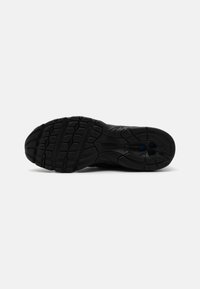 Svart idrettssko såle laget av gummimateriale; har dype mønstre og avrundede kanter; inkluderer merkevare og ventilasjonsåpninger.