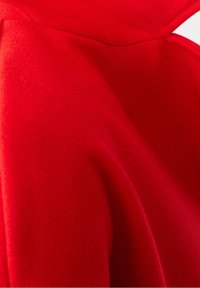 Tissu en polaire rouge avec une texture lisse, présentant des plis drapés et une légère brillance. Conçu avec un col haut pour plus de chaleur.