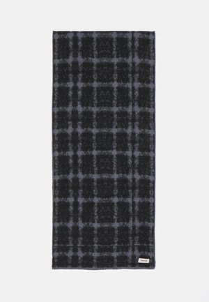 Écharpe en laine à carreaux noirs et gris avec une texture douce, de forme rectangulaire, et une petite étiquette de marque dans un coin, sur fond blanc.