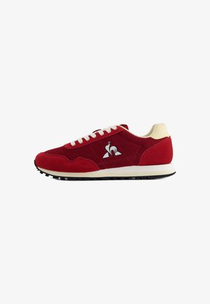 Zapatilla deportiva roja con upper de malla, acentos de ante, cordones beige y suela de goma negra con dibujo. Logo en el lateral.