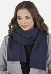 Marineblaues Strickschal mit glatter Textur, um den Hals gelegt. Weiches Material mit einem sauberen, gleichmäßigen Finish und dezenten Fransenrändern.