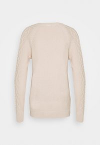 Pull en maille beige pâle avec des motifs en relief le long des manches et un ourlet inférieur côtelé. Col rond et manches longues.