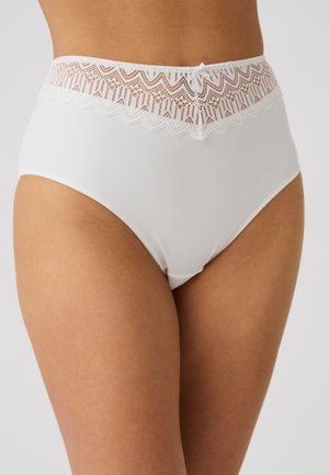 Sous-vêtements blancs taille haute avec ceinture en dentelle et petit nœud porté par une personne à la peau brun clair sur fond uni.