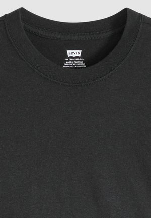 Camiseta negra de algodón con cuello redondo y ribete acanalado, que presenta una etiqueta interior con información de la marca y cuidados. Textura suave.