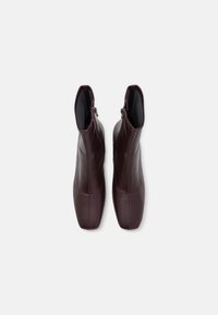 Bottines en cuir bordeaux à finition lisse, avec un bout pointu et des fermetures éclair latérales. Détails de coutures sur les côtés et une doublure intérieure douce.