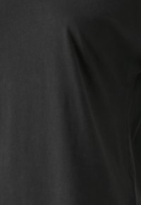 Czarna tkanina z delikatnymi fałdami i lekko błyszczącą teksturą, sugerująca gładki, miękki materiał.