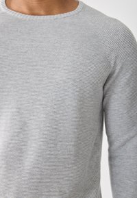 Suéter gris de punto, con cuello redondo y mangas largas. Presenta un patrón de rayas horizontales y un acabado de tela texturizada.