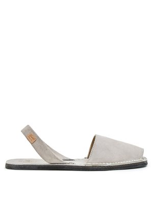 Sandalia plana de ante gris claro con puntera abierta, correa trasera y suela negra, vista de lado sobre fondo blanco.