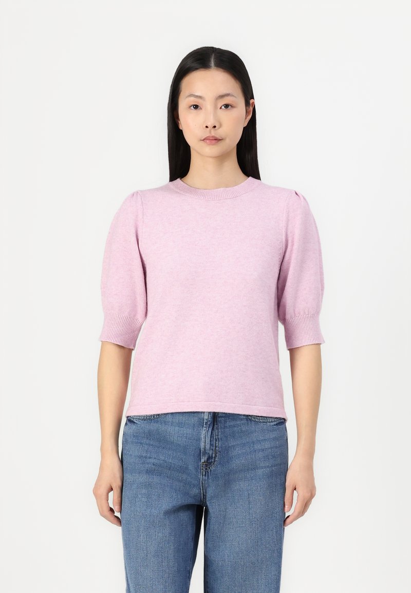 Light pink knitted sweater with short puffed sleeves, round neckline, and ribbed accents. Paired with blue denim jeans.