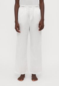 Weißes, weites Bein-Futteral aus glattem Stoff mit elastischem Bund. Mit einem Logo-Band am Taillenbund und einer geraden, fließenden Silhouette.