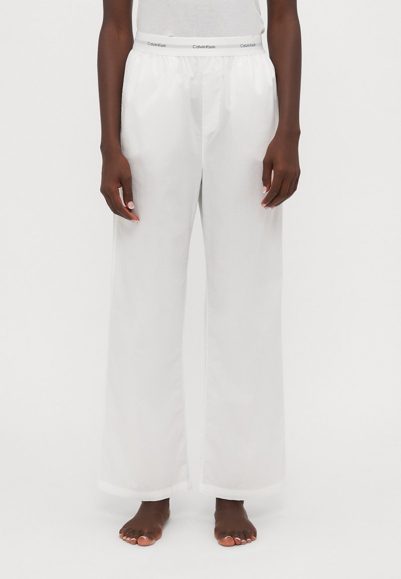 Weißes, weites Bein-Futteral aus glattem Stoff mit elastischem Bund. Mit einem Logo-Band am Taillenbund und einer geraden, fließenden Silhouette.