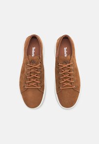 Bruna lädersneakers med en slät yta, rund tå, vit gummisula och bruna snören; har varumärkets logga på innersulan.