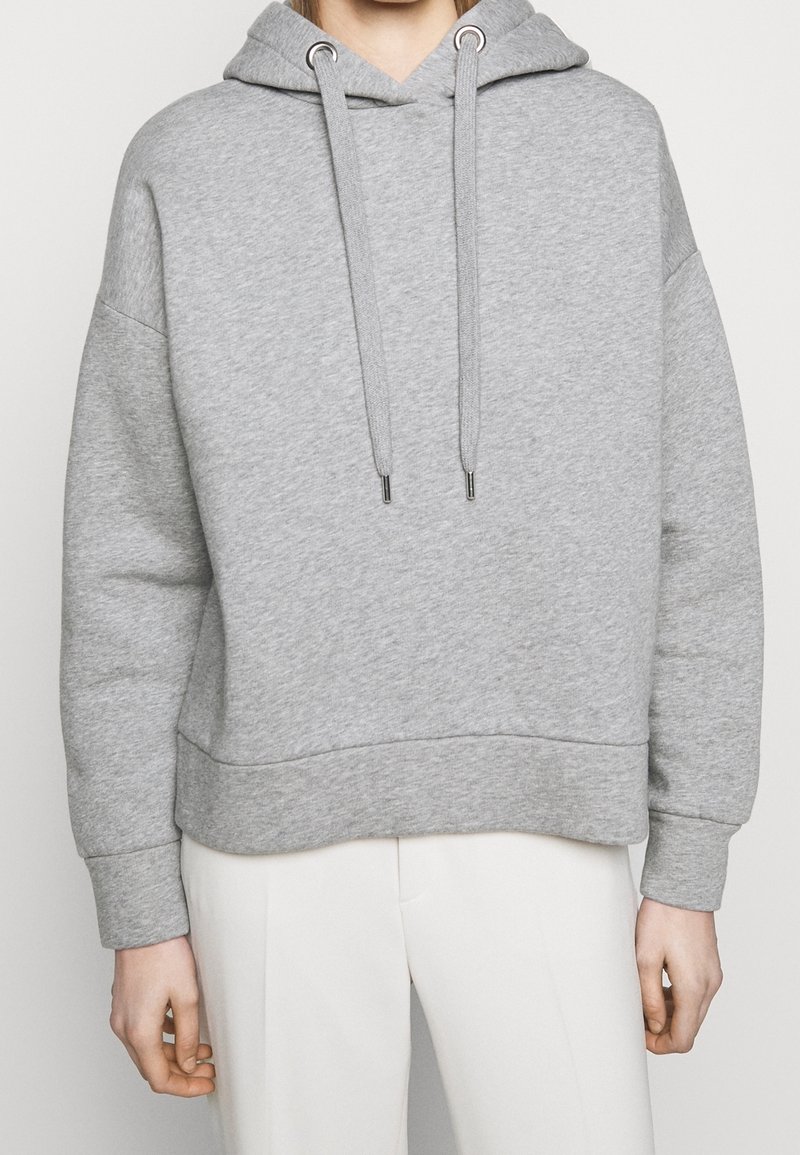 Sudadera con capucha gris hecha de una tela suave, con un corte holgado, cordones y puños de canalé. Diseño sencillo de color sólido.