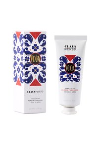 Handcreme in einer weißen Tube mit blauem Blumenmuster und schwarzem Text. Begleitet von einer dekorativen, gemusterten Schachtel in Blau, Rot und Weiß.