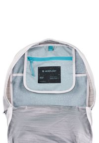 L'interno dello zaino grigio chiaro presenta un motivo geometrico, una tasca con zip blu e un'etichetta nera. Un tessuto morbido e testurizzato foderava la borsa.