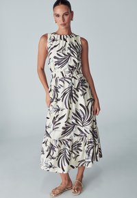 Brezrokavni maksi obleka v kremni barvi z črnim cvetličnim vzorcem, z elastičnim pasom, plastmi ruffles na robu in stranskimi žepi.