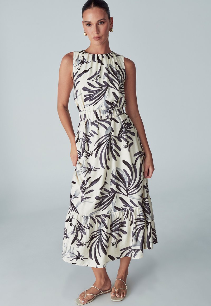 Brezrokavni maksi obleka v kremni barvi z črnim cvetličnim vzorcem, z elastičnim pasom, plastmi ruffles na robu in stranskimi žepi.