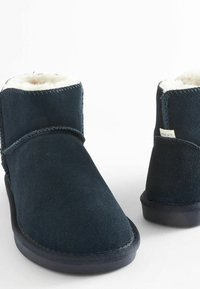 Navy blue suede ankle boots featuring a faux fur lining, rounded toe, and contrasting stitching. Includes a small label on the side.