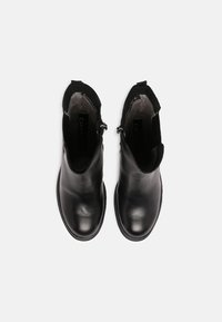 Czarne skórzane botki za kostkę o eleganckim designie, zaokrąglonym nosku i elastycznych bocznych panelach. Subtelne detale przeszycia i gładka faktura.