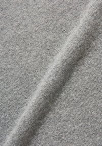 Hellgrauer Stoff mit weicher Textur, der ein subtiles, leicht meliertes Aussehen und ein glattes, gedehntes Muster aufweist.