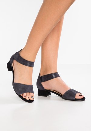 Donkerblauwe suède sandalen met een open teen, enkelriem en lage blokhak. Glad oppervlak en minimalistisch ontwerp.